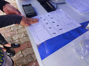 policyjne urządzenie do pobierania odcisków palców i dziecko wykonujące odciski na papierze
