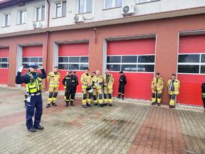 policjant podczas szkolenia strażaków na placu przy budynku straży pożarnej