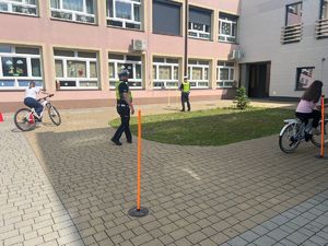 policjanci podczas prowadzenia egzaminu na kartę rowerową dzieci jeżdżą na rowerach na placu przed szkołą