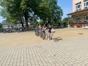 policjanci podczas prowadzenia egzaminu na kartę rowerową dzieci jeżdżą na rowerach na placu przed szkołą