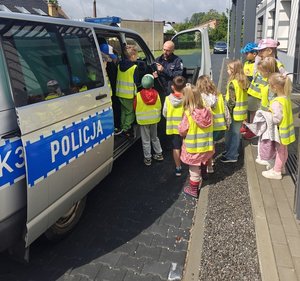 dzieci podczas oglądania policyjnego radiowozu przy budynku policji