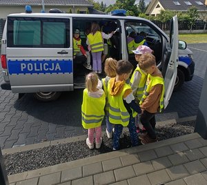 dzieci podczas oglądania policyjnego radiowozu przy budynku policji