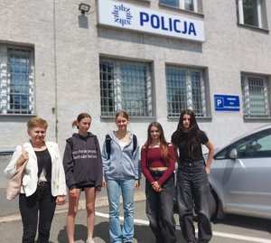 uczennice z nauczycielka stoją przy budynku policji