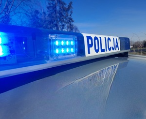 belka policyjnego radiowozu z włączonymi niebieskimi światłami błyskowymi z napisem policja