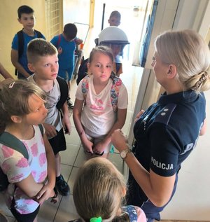 dzieci z policjantką na korytarzu w budynku komendy policji