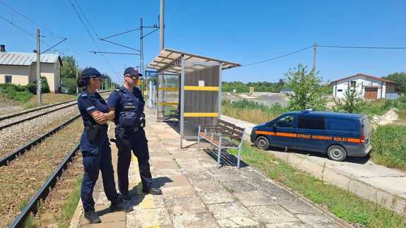 przy przejeździe kolejowym policjantka i policjant służby ochrony kolei w tle pojazd sok