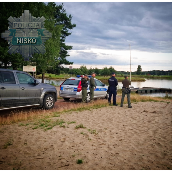 policjanci i funkcjonariusze strazy rybackiej stoją przy zbiorniku wodnym