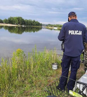 policjant razem z wędkarzem nad zbiornikiem wodnym