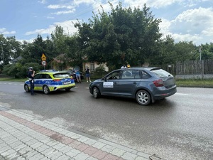 policyjny radiowóz na trasie wyścigu kolarskiego za nim samochód osobowy