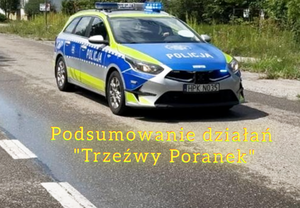 policyjny radiowóz stoi na jezdni pod spodem napis policyjne działania trzeźwy poranek