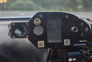 policyjny miernik prędkości z wyświetloną wartością 106 km/h leży na desce rozdzielczej radiowozu