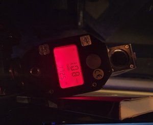 policyjny miernik prędkości z wyświetloną wartością 108 km/h leży na desce rozdzielczej radiowozu