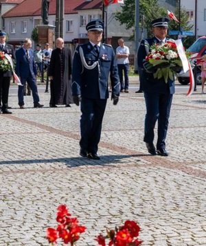 policjanci idą z wiązanką pod pomnik
