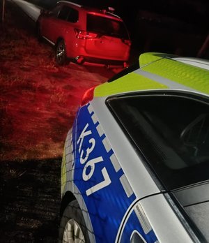policyjny radiowóz na skraju drogo za nim pojazd osobowy który kontroluje policjant pora nocna