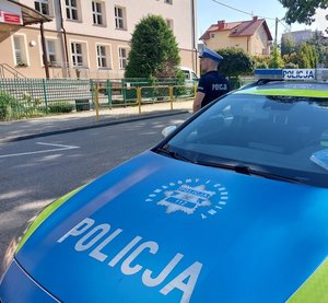 policyjny radiowóz na poboczu naprzeciwko budynku szkoły