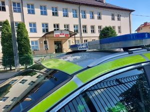 policyjny radiowóz w pobliżu budynku szkoły