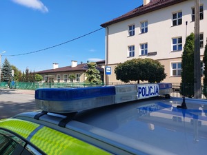 policyjny radiowóz obok budynku szkoły na poboczu