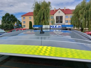 policyjny radiowóz obok budynku szkoły