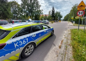 policyjny radiowóz obok budynku szkoły na poboczu