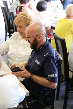 policjant siedzi z seniorką przy stole rozmawiają