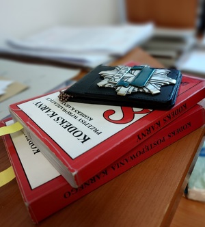 na stole leży kodeks karny a na nim policyjna legitymacja