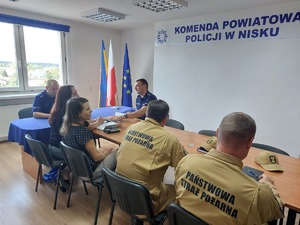 policjanci, strażacy oraz osoby cywilne siedzą przy stole