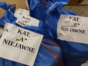 worki foliowe koloru niebieskiego z przyczepionymi kartkami na których są napisy jawne i niejawne