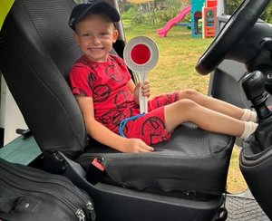 chłopczyk siedzi za kierownicą radiowozu w ręku trzyma tarczę do zatrzymywania policjantów