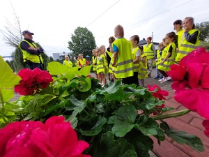 policjant stoi przed grupą dzieci ubranych w kamizelki odblaskowe