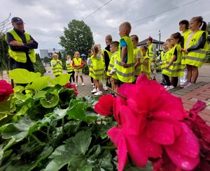 policjant stoi przed grupą dzieci ubranych  w kamizelki odblaskowe