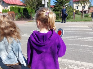 dziewczynki z tarczą do zatrzymywania pojazdów przed przejściem dla pieszych w tle policjantka