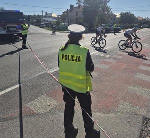 policjantka stoi na jezdni w tle jadą kolarze