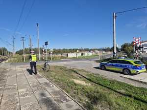 Policjant stoi przy przejeździe kolejowym.