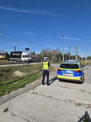 Policjant stoi przy radiowozie.