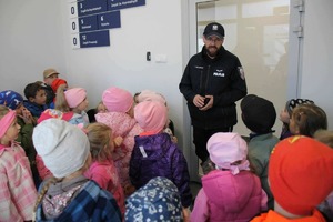 Policjant stoi przed dziećmi i mówi.