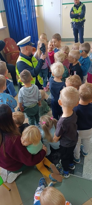 Policjant pokazuje dzieciom urządzenie do pomiaru prędkości.