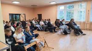 Dzieci siedzą na krzesłach i słuchają policjantki.