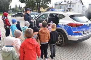 Dzieci oglądają radiowóz, w którym otworzone są drzwi.