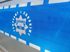 Naklejka na boku radiowozu z napisem &amp;quot; Pomagamy i Chronimy&amp;quot;.