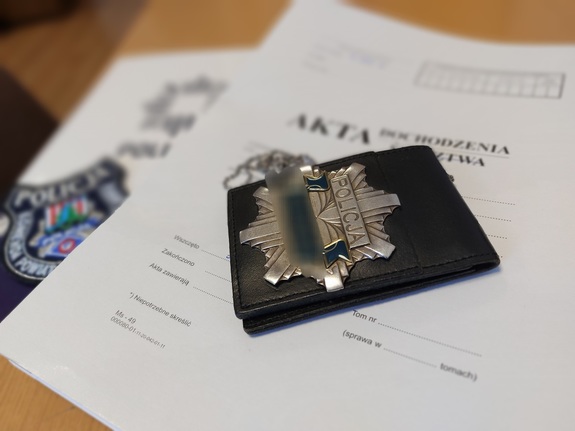 teczka akt na której leży emblemat z napisem &quot;KPP Nisko&quot; oraz legitymacja policyjna.