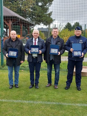Komendant Powiatowy Policji w Nisku wraz z lokalnymi włodarzami stoją i trzymają w ręce upominki - podziękowania.