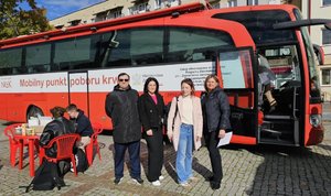 Policjantki, pracownik cywilny i organizator wydarzenia na tle czerwonego autobusu