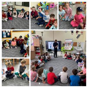 Dzieci siedzą na wykładzinie i słuchają, policjantka stoi i mówi do dzieci.