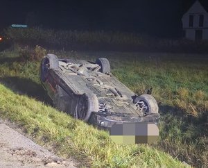 samochód osobowy leży na dachu w przydrożnym rowie