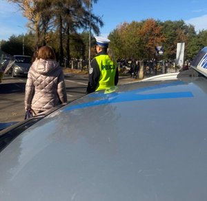 Policjantka nadzoruje ruch na drodze i pomaga pieszym przejść przez drogę