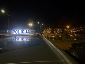 belka świetlno-dźwiękowa z napisem Policja w tle rozświetlony cmentarz