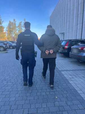 Policjant prowadzi zatrzymanego mężczyznę