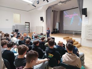młodzież siedzi i słucha prelekcji przeprowadzanej przez policjantkę