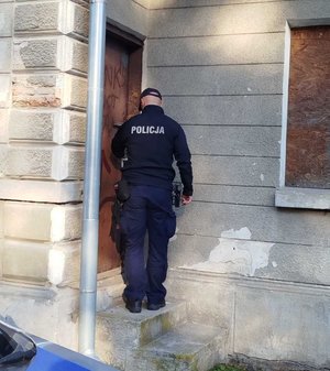 Policjant trzyma za klamkę drzwi