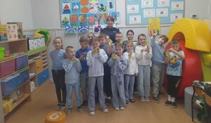 Policjantka stoi z dziećmi na tle tablic.